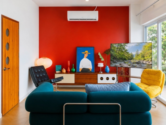 Living room with red feature wall, teal sofa and yellow armchair in a 2-bedroom villa in Sisattanak, Vientiane