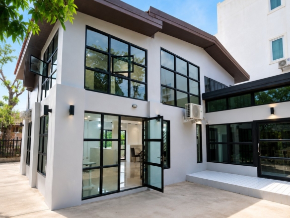 Two-storey white villa with black-framed windows and terrace in the expat area of Vientiane