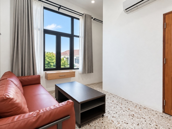Bright living room with leather sofa and large window – new apartment, city center, Vientiane